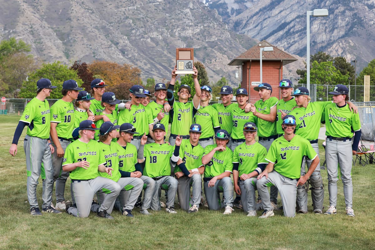 Timpanogos players holding a region championship trophy with the mountains behind them